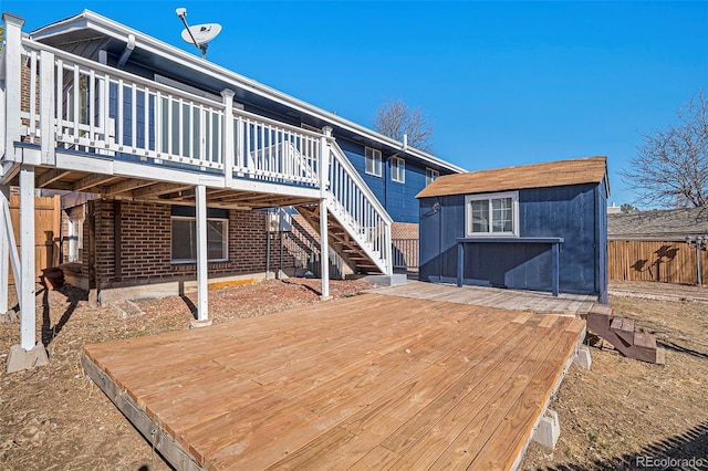 rear view of property featuring a wooden deck, fence, an outbuilding, and brick siding