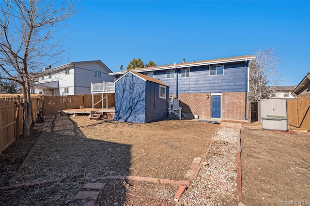 rear view of property featuring a shed, an outdoor structure, a fenced backyard, and brick siding