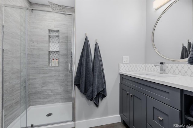 bathroom featuring a stall shower, baseboards, vanity, and decorative backsplash