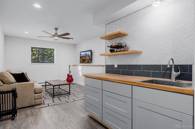 kitchen with a sink, butcher block countertops, wood finished floors, recessed lighting, and a ceiling fan