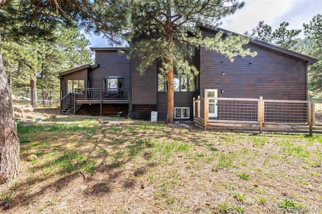 back of house featuring stairs, a wooden deck, and fence