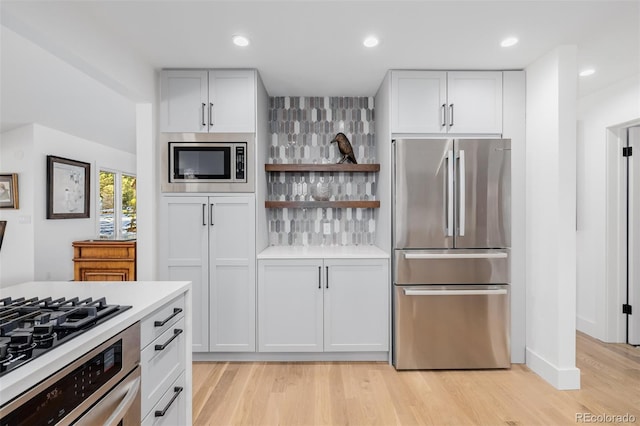 kitchen featuring recessed lighting, stainless steel appliances, white cabinetry, light countertops, and light wood-type flooring