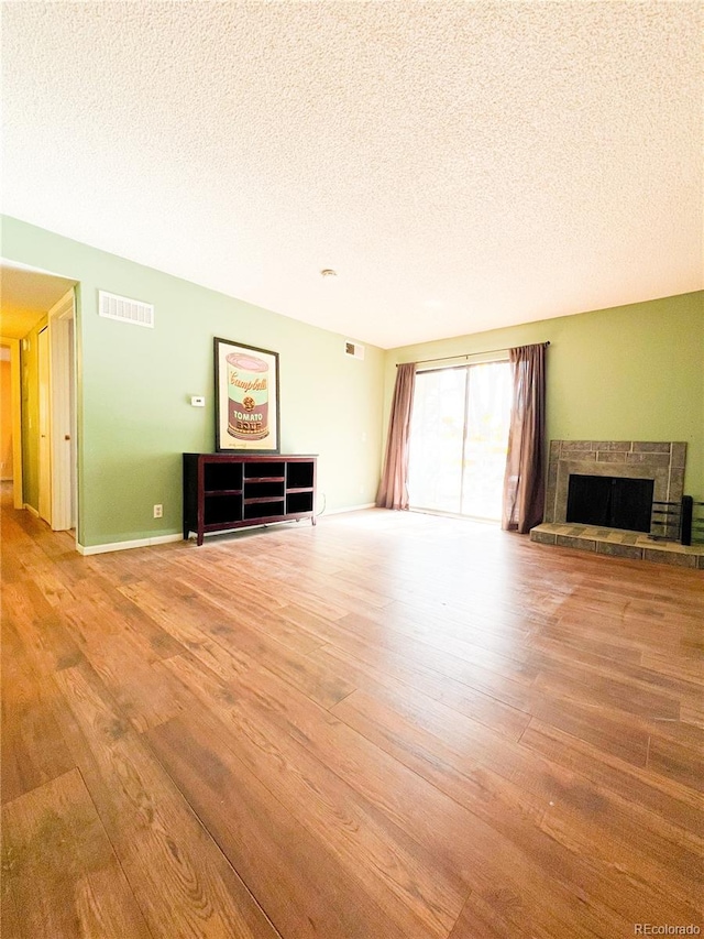 unfurnished living room with light hardwood / wood-style flooring, a textured ceiling, and a fireplace