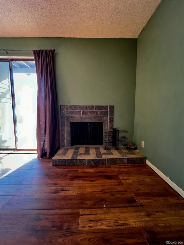 living room featuring a textured ceiling, wood-type flooring, and a fireplace