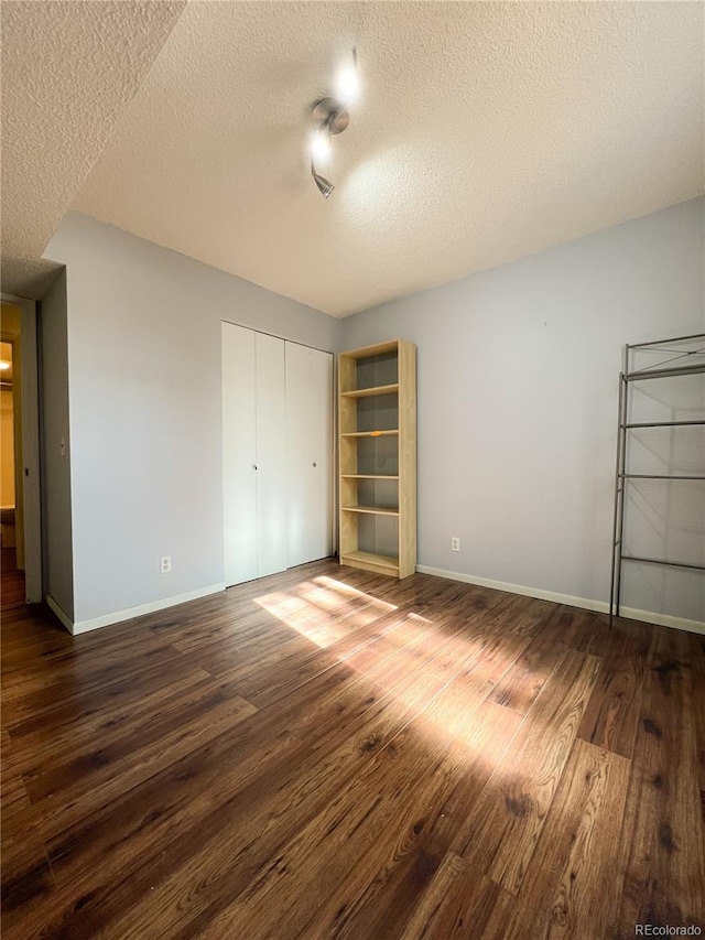 unfurnished bedroom featuring dark wood-type flooring and a textured ceiling