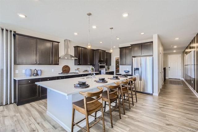 1320 Loraine Cir N, Lafayette, CO 80026 - kitchen featuring appliances with stainless steel finishes, wall chimney exhaust hood, a sink, light wood-style floors, and dark brown cabinets