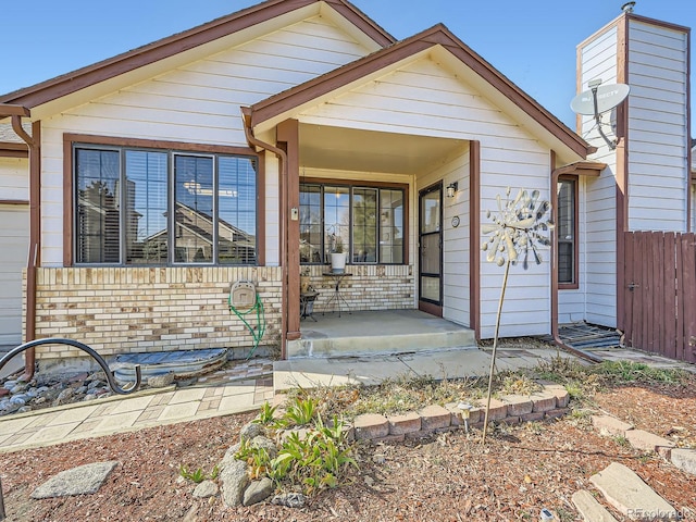 view of front of home with a porch, fence, and brick siding