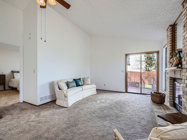 carpeted living room with baseboards, visible vents, a textured ceiling, a brick fireplace, and high vaulted ceiling