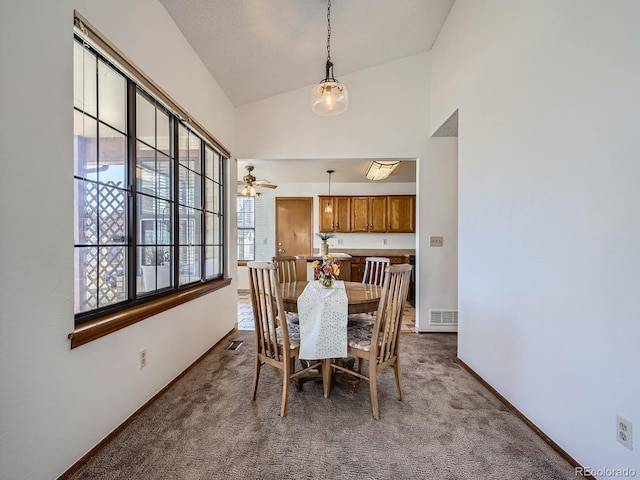 dining area with high vaulted ceiling, visible vents, dark carpet, and baseboards