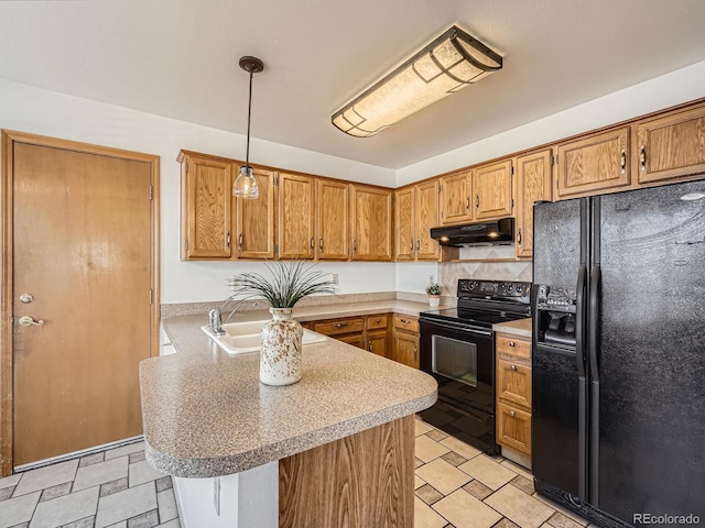 kitchen featuring under cabinet range hood, a peninsula, a sink, light countertops, and black appliances