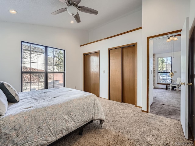 carpeted bedroom with ceiling fan, a textured ceiling, two closets, and recessed lighting