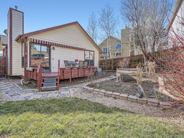 back of house featuring fence, a chimney, and a wooden deck