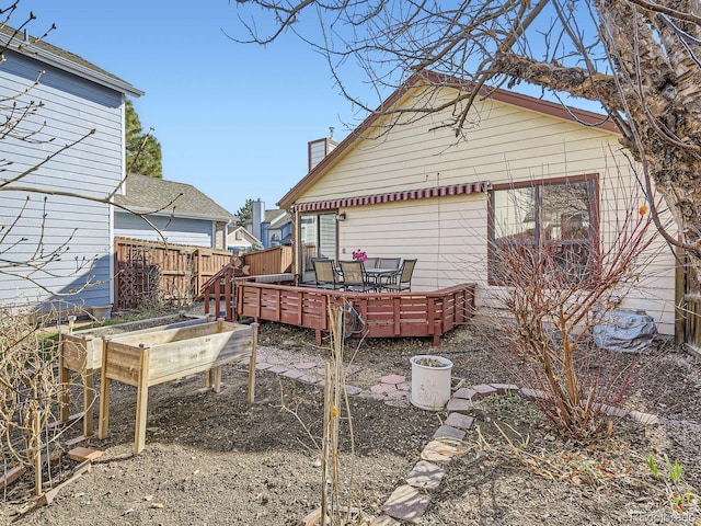 back of property featuring a vegetable garden, fence, and a wooden deck