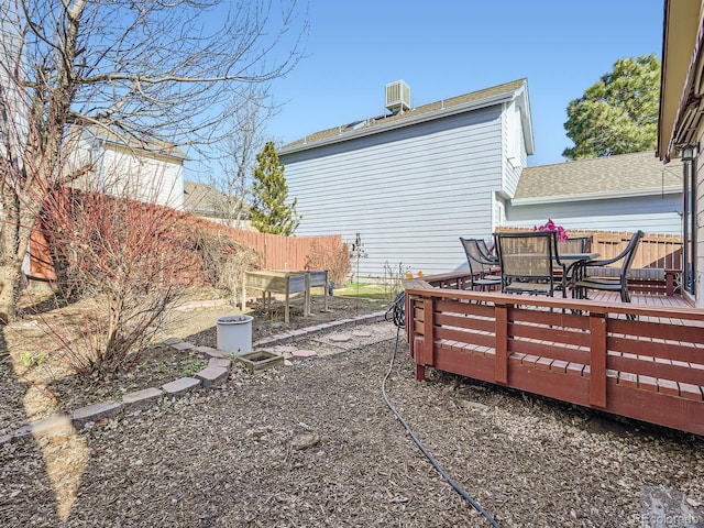 view of yard with outdoor dining space, central AC unit, fence, and a wooden deck