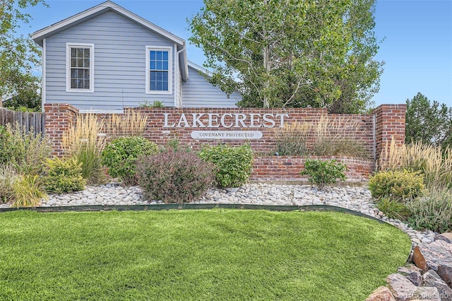 community / neighborhood sign featuring a yard and fence