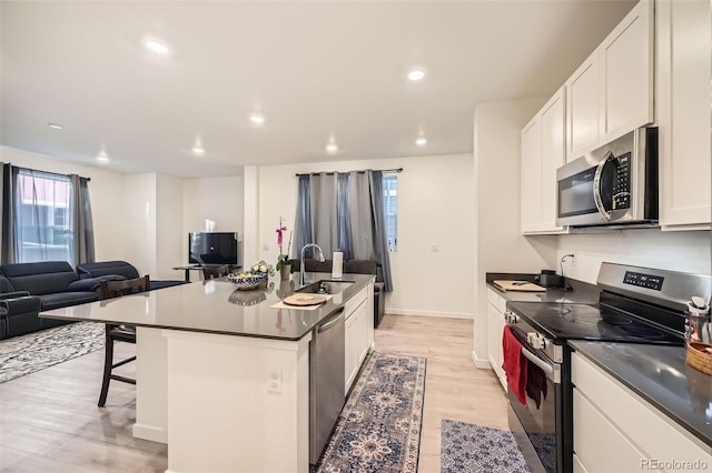 kitchen with appliances with stainless steel finishes, sink, white cabinets, a breakfast bar, and an island with sink