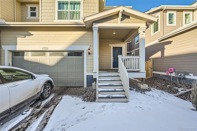 snow covered property entrance with a garage