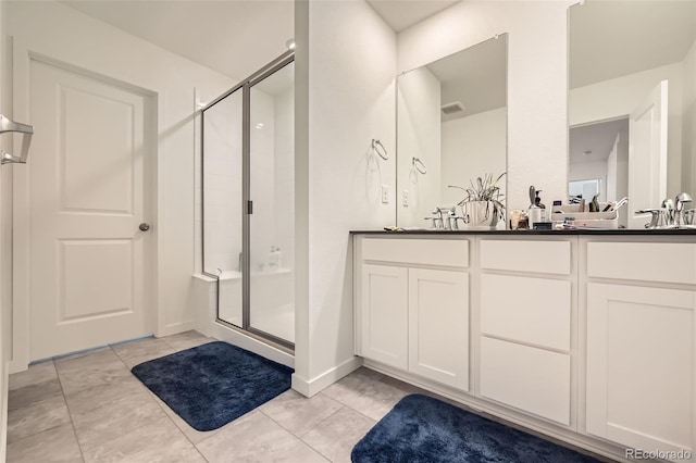 bathroom featuring tile patterned floors, a shower with door, and vanity