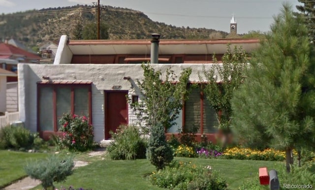 view of front of house with a front yard and a mountain view