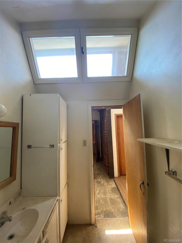 bathroom featuring tile flooring, sink, and a skylight