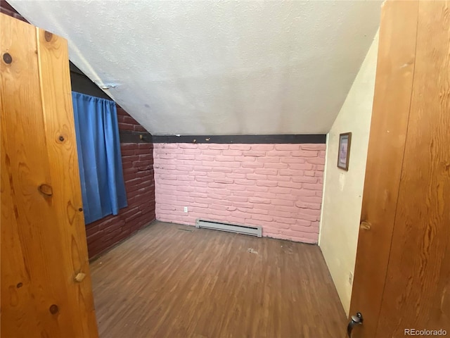 additional living space featuring brick wall, a baseboard radiator, wood-type flooring, a textured ceiling, and lofted ceiling