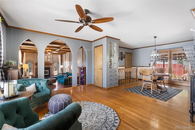 living room with coffered ceiling, ceiling fan with notable chandelier, crown molding, wood-type flooring, and beamed ceiling