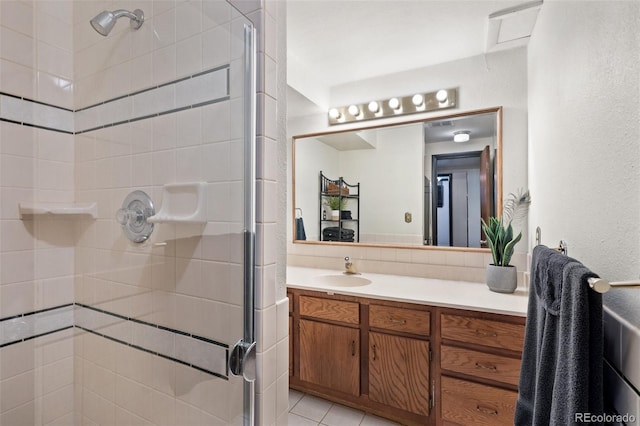 bathroom with tasteful backsplash, tile patterned floors, a shower with door, and vanity