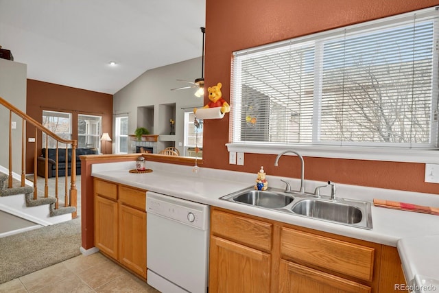 kitchen with dishwasher, vaulted ceiling, light countertops, a sink, and light tile patterned flooring