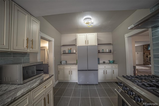 kitchen with stainless steel appliances, light stone countertops, dark tile patterned flooring, and decorative backsplash