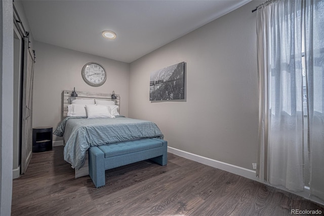 bedroom with dark hardwood / wood-style floors and a barn door