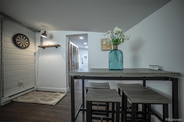 dining area with dark wood-type flooring, vaulted ceiling, and a baseboard heating unit