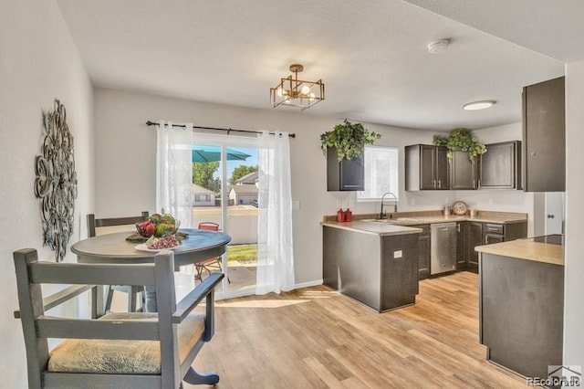 kitchen with dark brown cabinetry, dishwasher, sink, light hardwood / wood-style flooring, and a chandelier