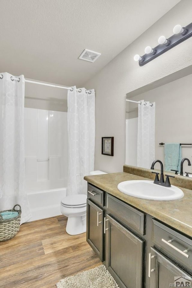 full bathroom with shower / bath combination with curtain, wood-type flooring, a textured ceiling, toilet, and vanity