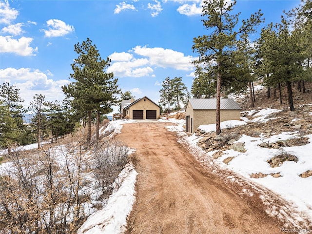 view of front of home featuring an outbuilding, a detached garage, dirt driveway, and stucco siding