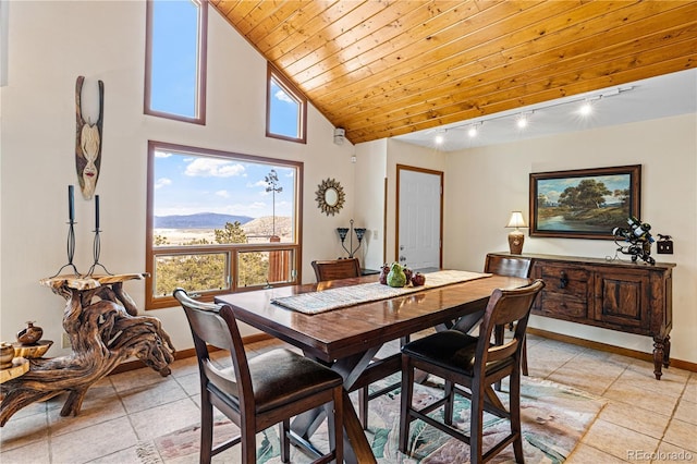 dining space with baseboards, wood ceiling, rail lighting, high vaulted ceiling, and a mountain view