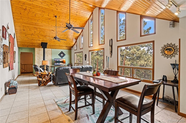 dining space with light tile patterned floors, rail lighting, wood ceiling, a wood stove, and baseboards