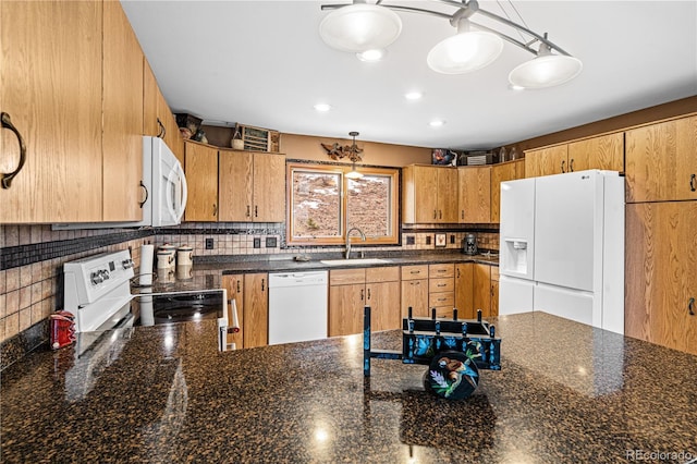 kitchen featuring decorative backsplash, a sink, dark stone countertops, white appliances, and a peninsula