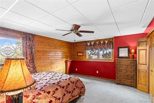 carpeted bedroom featuring a paneled ceiling, ceiling fan, and wooden walls