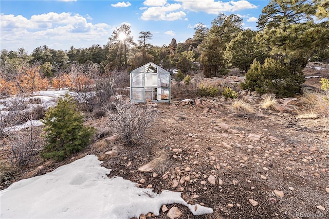 view of yard with a greenhouse, an outdoor structure, and a forest view