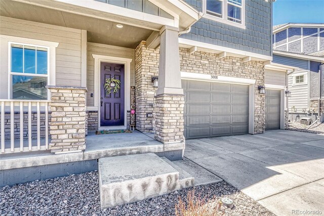 property entrance with stone siding, an attached garage, and concrete driveway