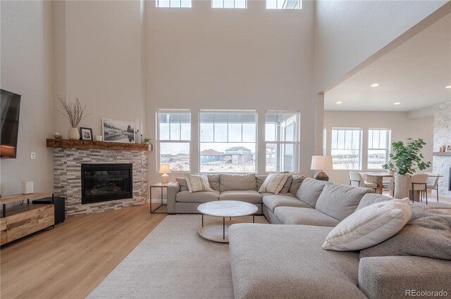 living area with wood finished floors, a towering ceiling, a fireplace, and recessed lighting