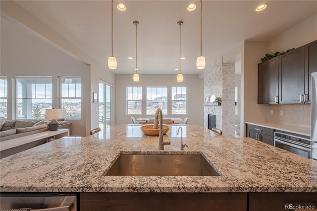 kitchen with dark brown cabinets, a center island with sink, open floor plan, and a sink