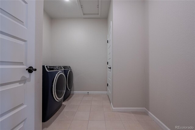 clothes washing area featuring washing machine and dryer, light tile patterned flooring, and baseboards