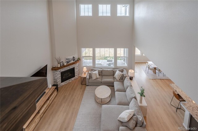 living area with a fireplace, a wealth of natural light, and light wood-style floors