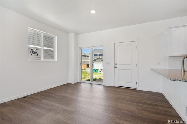unfurnished dining area featuring dark wood-type flooring, baseboards, and recessed lighting