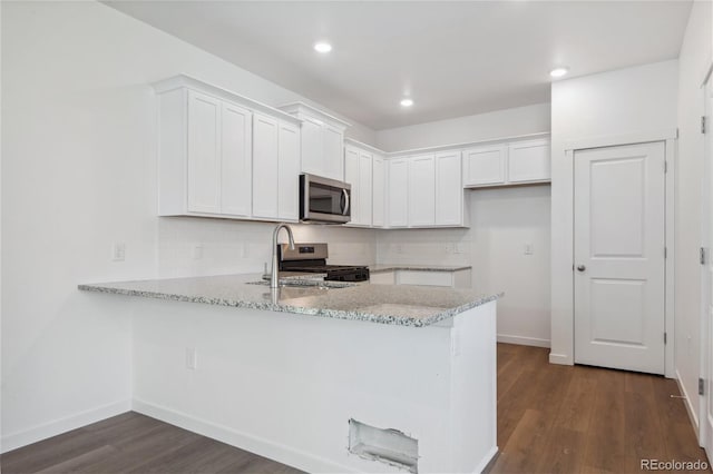 kitchen with stainless steel appliances, a peninsula, white cabinetry, dark wood-style floors, and recessed lighting