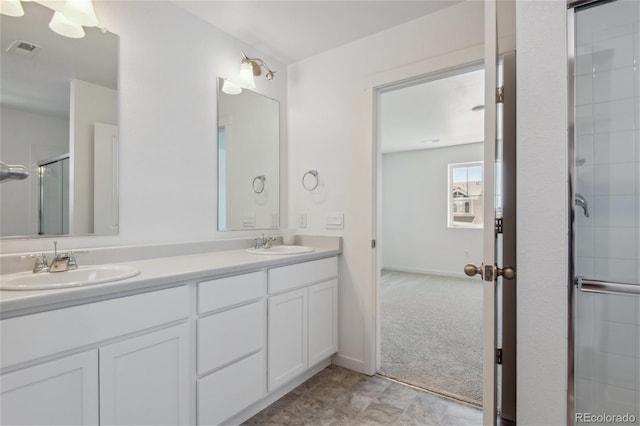 bathroom with a tile shower, double vanity, and baseboards