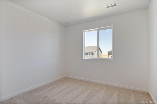 unfurnished room with light colored carpet and baseboards