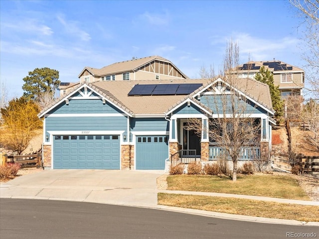 craftsman-style home featuring a garage, driveway, a front lawn, and roof mounted solar panels