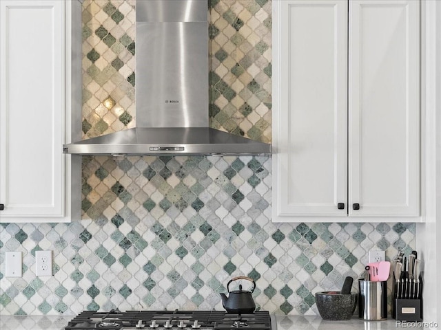 kitchen featuring white cabinets and wall chimney range hood